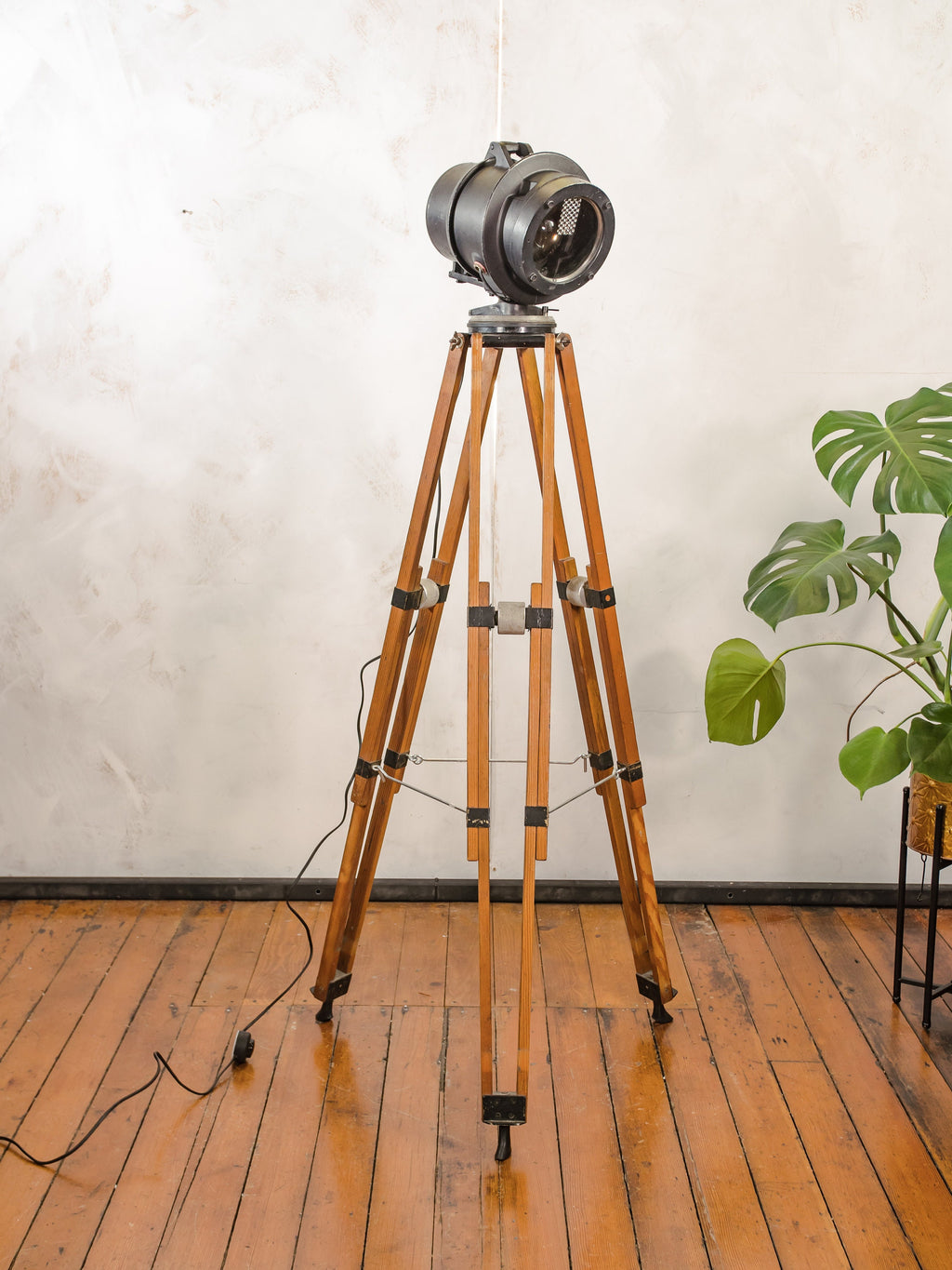 Zwarte spoorweg vloerlamp uit de jaren 50, hergebruikt signaallicht op een vintage houten videografiestatief, industriële staande lamp