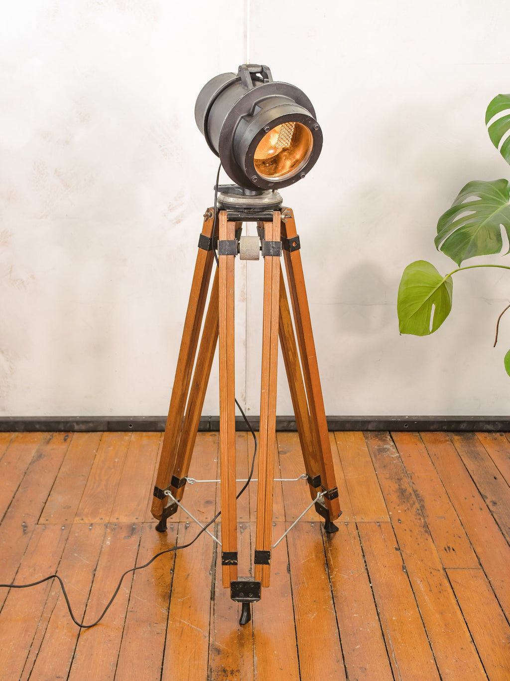 Zwarte spoorweg vloerlamp uit de jaren 50, hergebruikt signaallicht op een vintage houten videografiestatief, industriële staande lamp